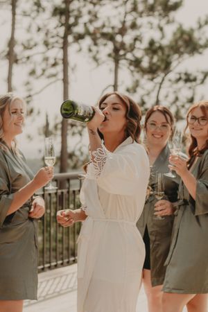 A bridal party celebrates with champagne on an outdoor terrace during a wedding celebration.