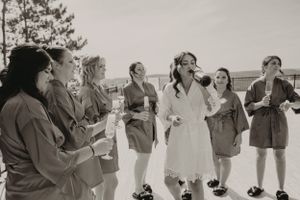 Black and white photo of a wedding party toasting with drinks in an outdoor setting.