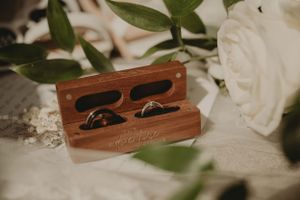 Wooden ring box with wedding bands nestled among white roses and lace.
