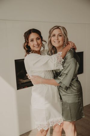 Two people embracing and smiling during wedding preparations in matching robes.
