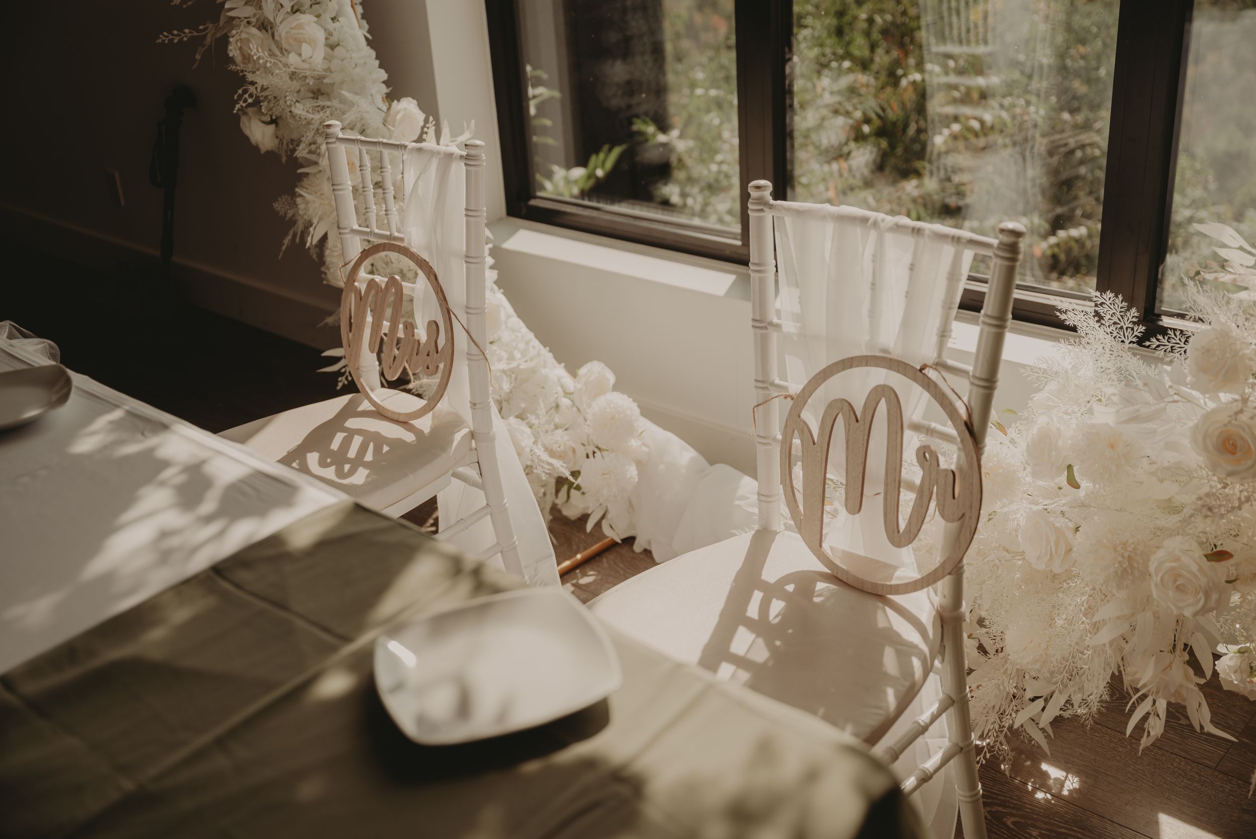 Decorated wedding chairs with monogram details in elegant white setting.