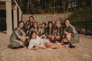 Wedding party in matching gray robes poses together on outdoor patio for group photo.