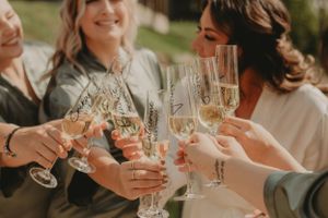 Wedding party toasting with champagne flutes in warm sunlight at an outdoor celebration.