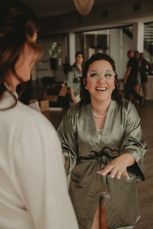 Wedding party member in silk robe laughing during pre-ceremony preparations.