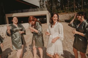 Candid celebration moment of wedding party in matching robes outdoors.