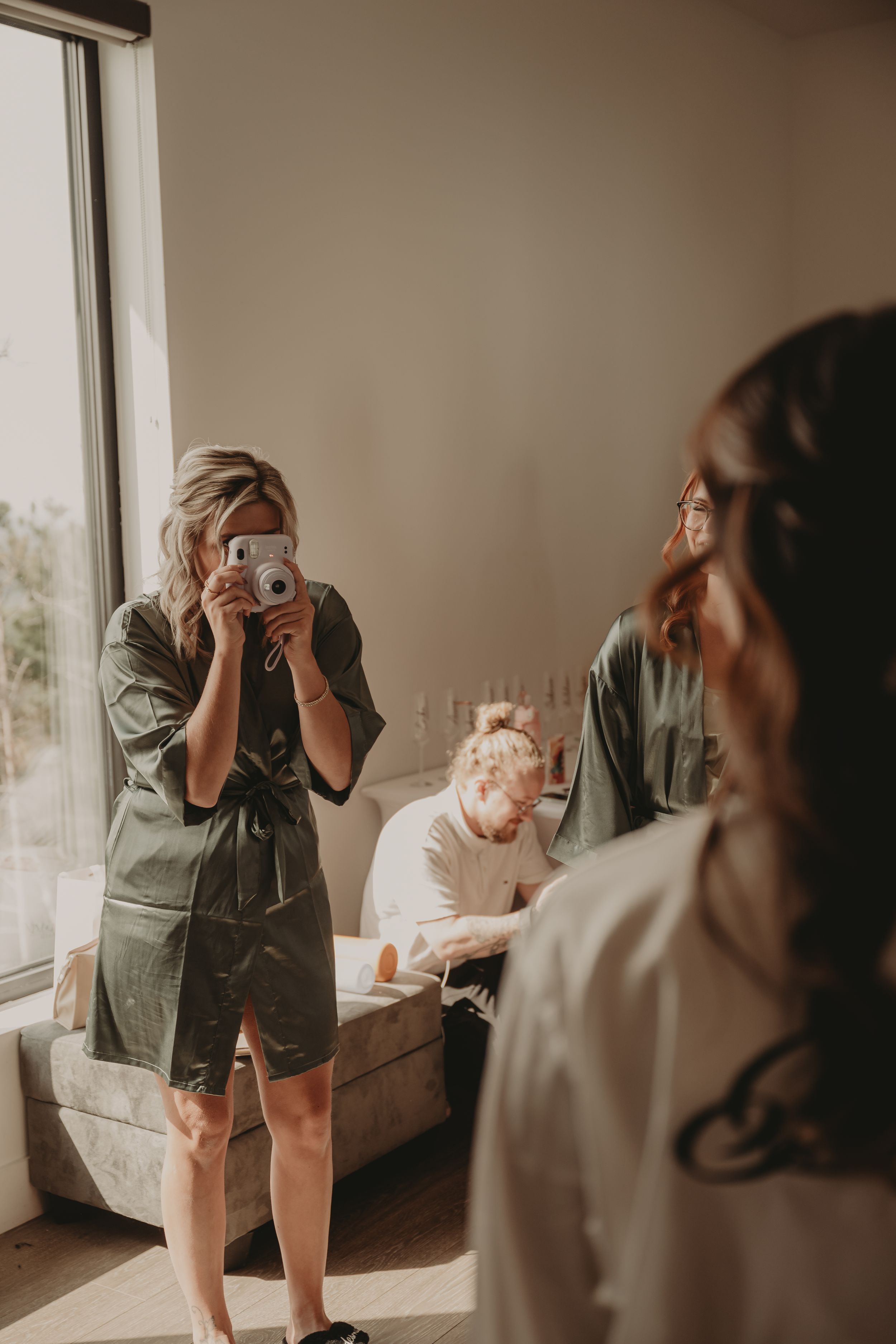 Wedding photographer takes pictures during preparations in a sunlit room.