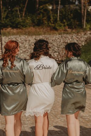 Three matching satin robes with 'bride' and 'bridesmaid' text photographed from behind.