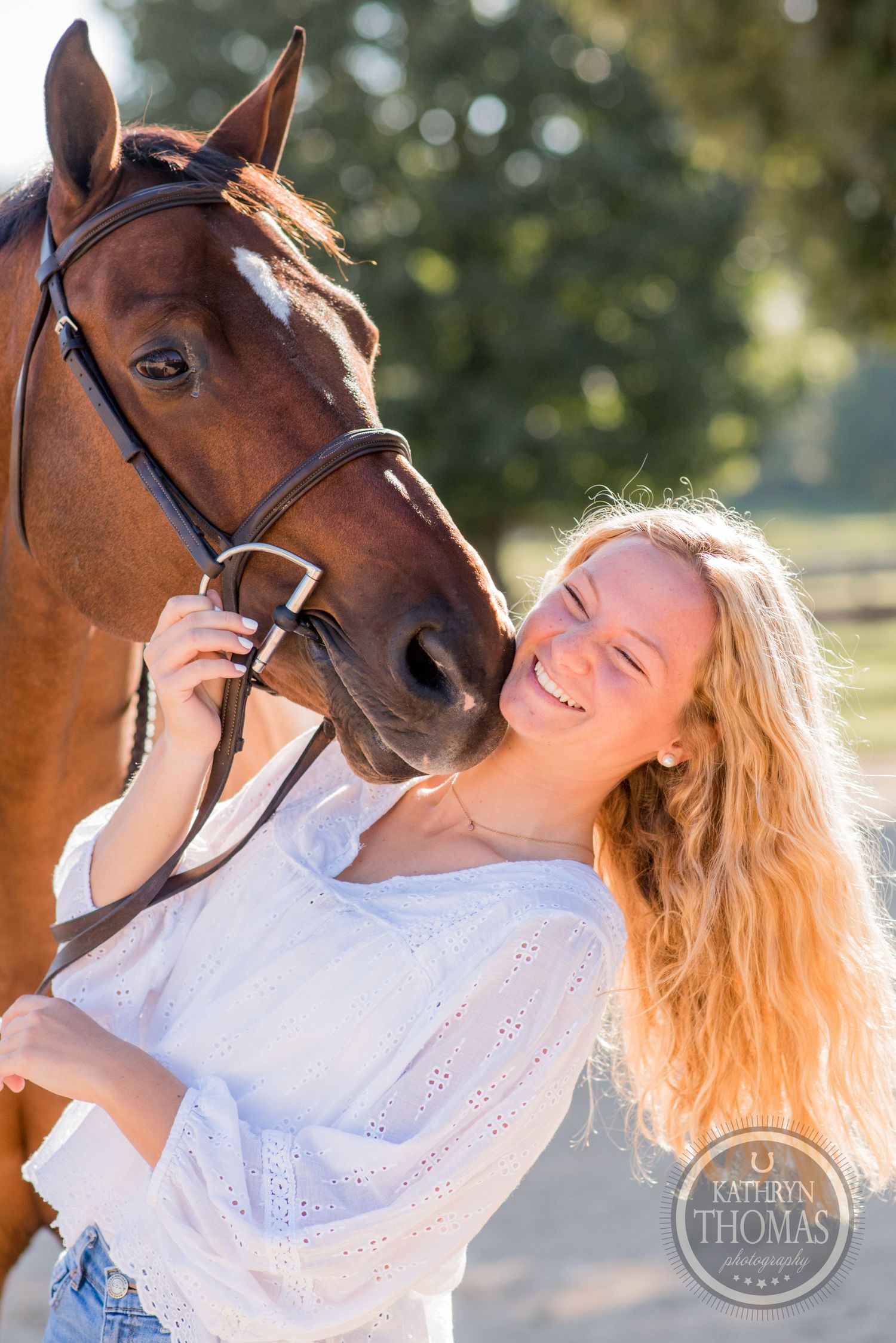 Close up of bay horse and person in white eyelet top sharing a joyful moment outdoors.