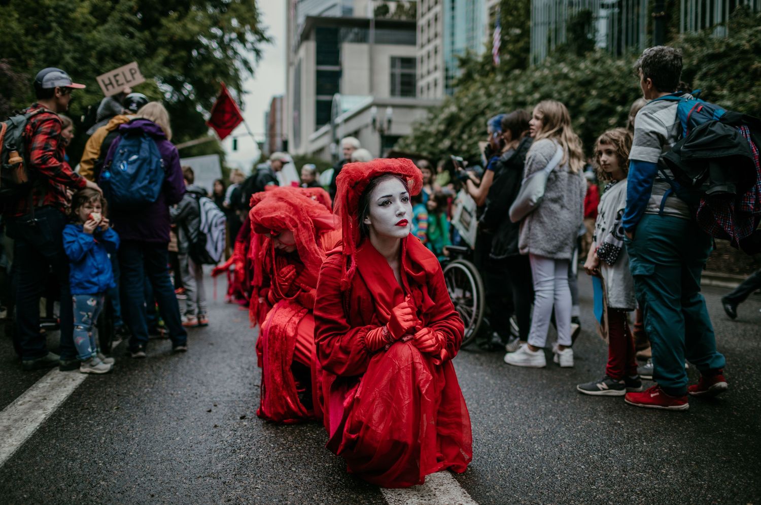 Climate justice activists in red costumes move through crowd performing silent art portland oregon