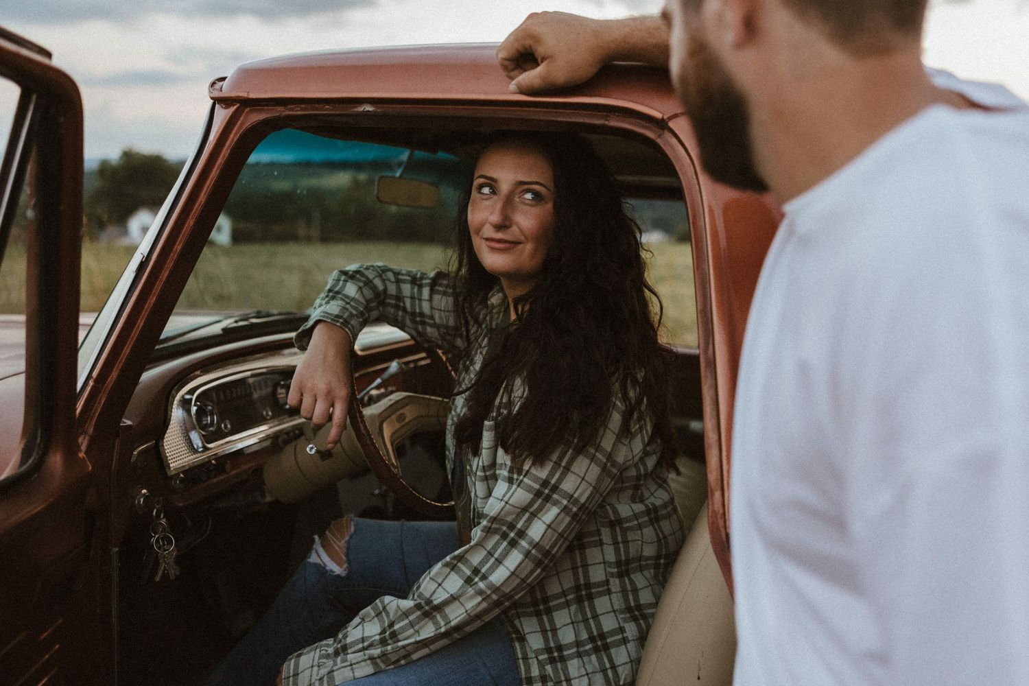 a woman in the drivers seat of a ford f100 truck looking back at boyfriend