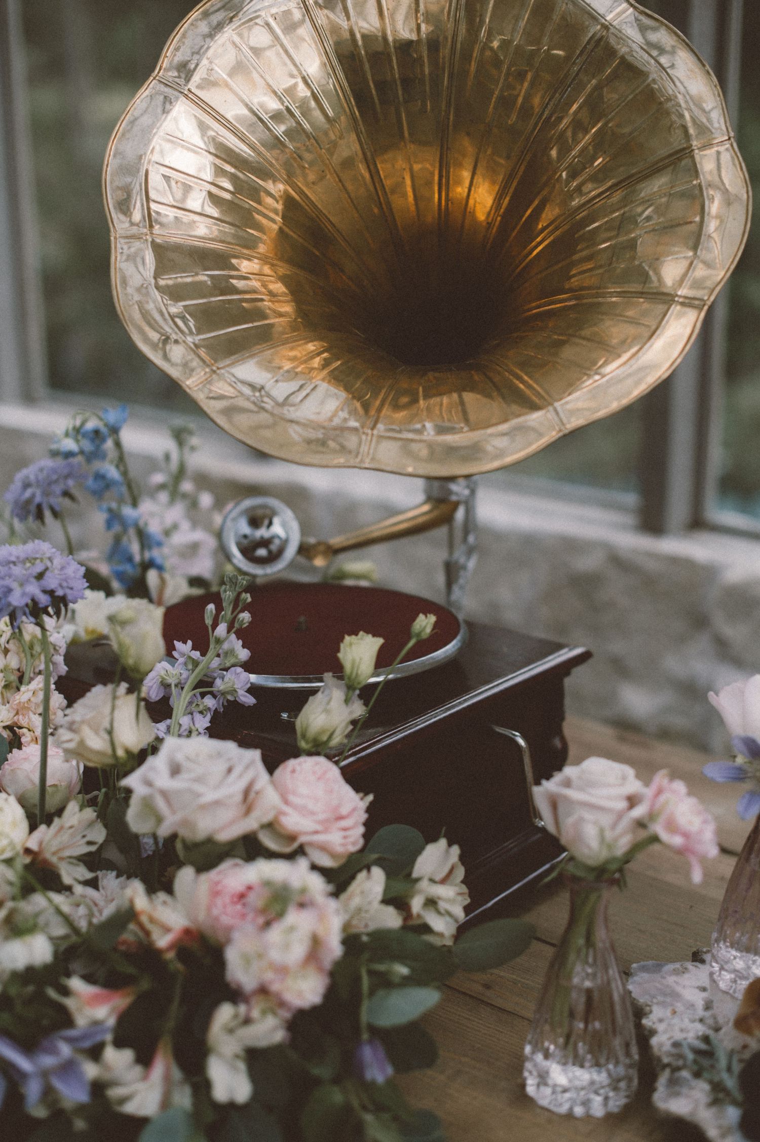 Vintage gramophone with pink and purple flowers arranged at its base.