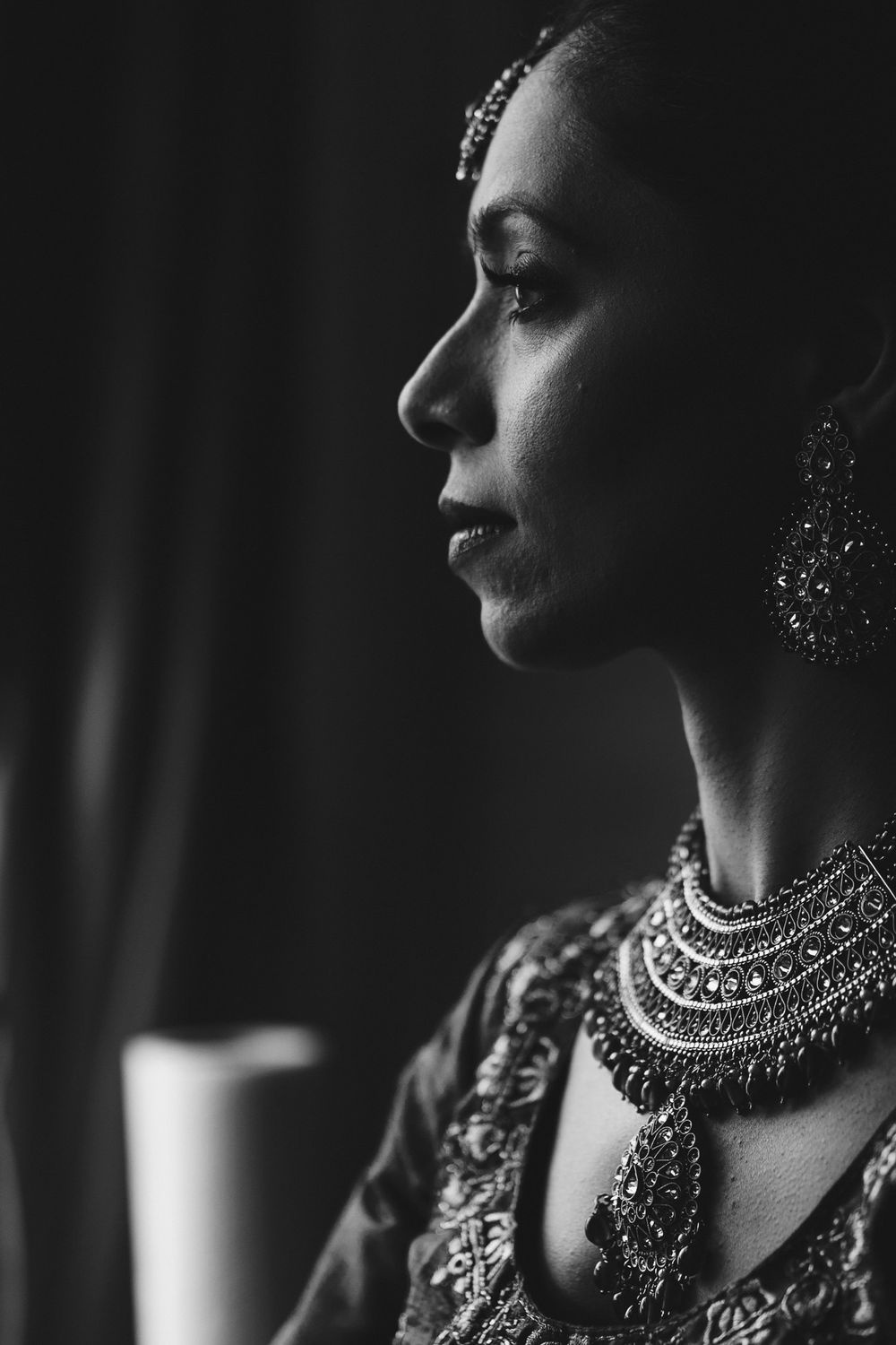 Dramatic black and white portrait showing ornate Indian bridal jewelry and traditional styling.