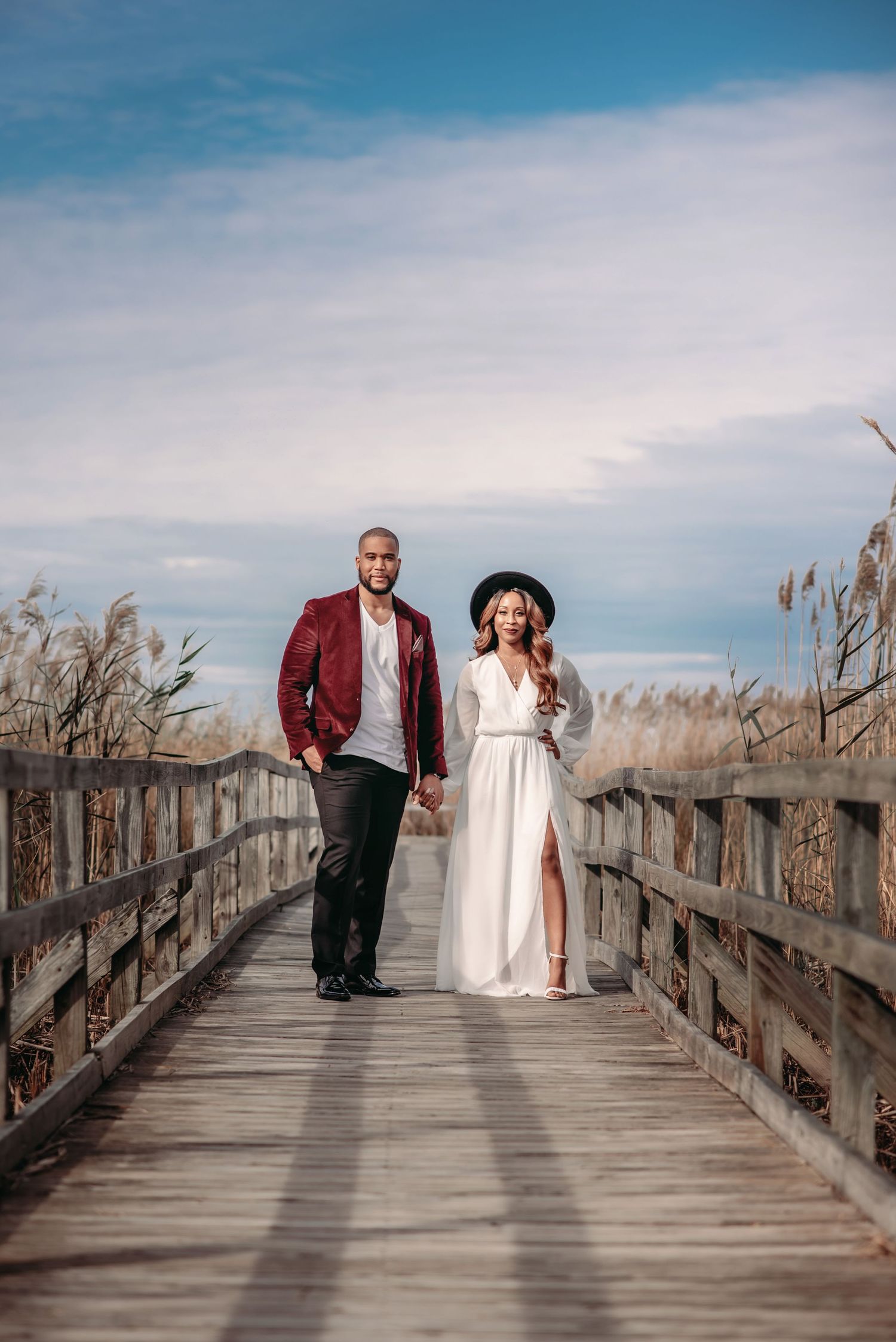 a photo of a newly married couple standing on a boardwalk at Back Bay National WIldlife Refuge