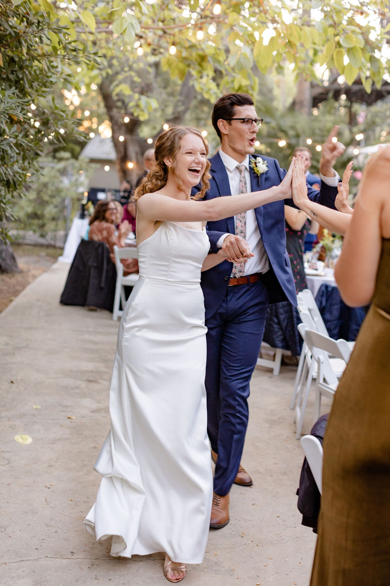 smiling couple just married pose outdoor venue high fiving guest