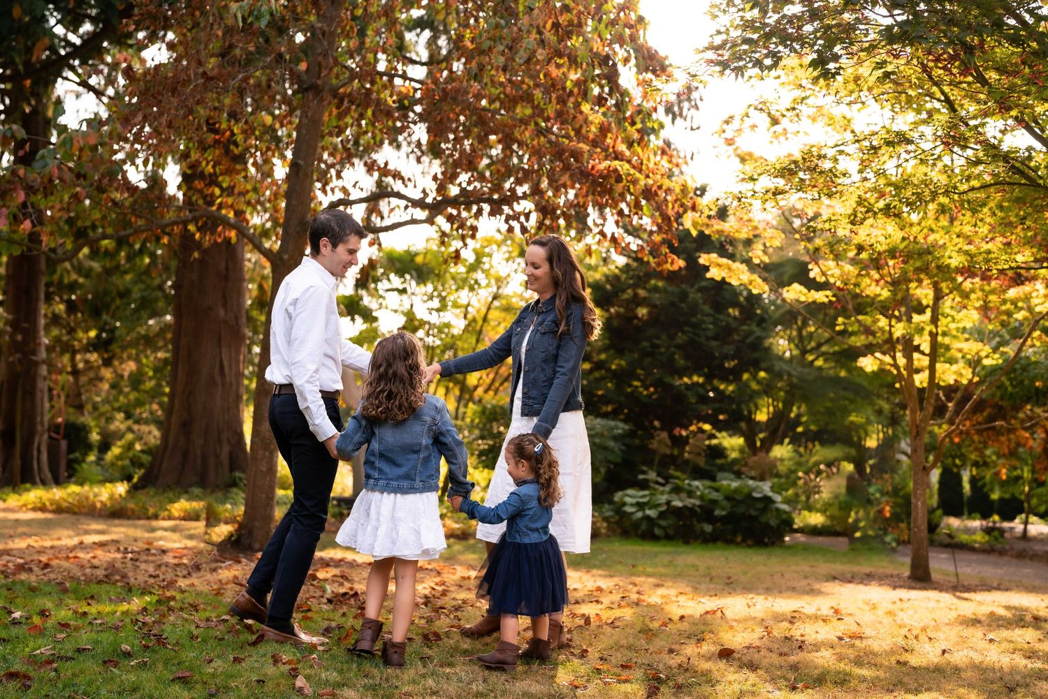 A joyful family moment captured in a sunlit autumn park setting.