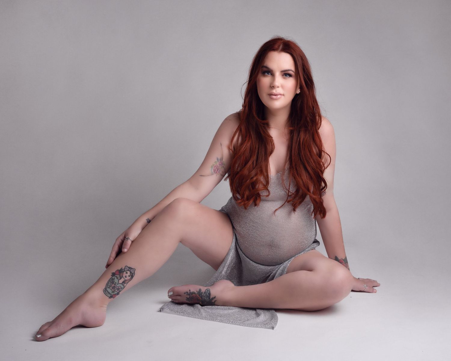 Studio portrait with minimalist grey backdrop showcasing elegant pose and artistic composition.
