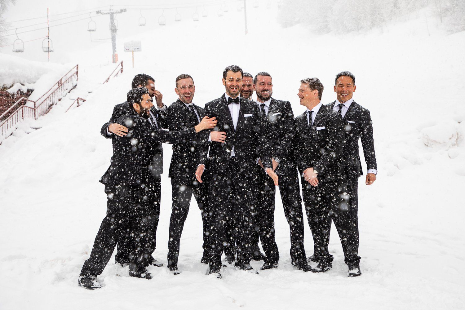 Group enjoying a snowy day together outdoors in formal attire.