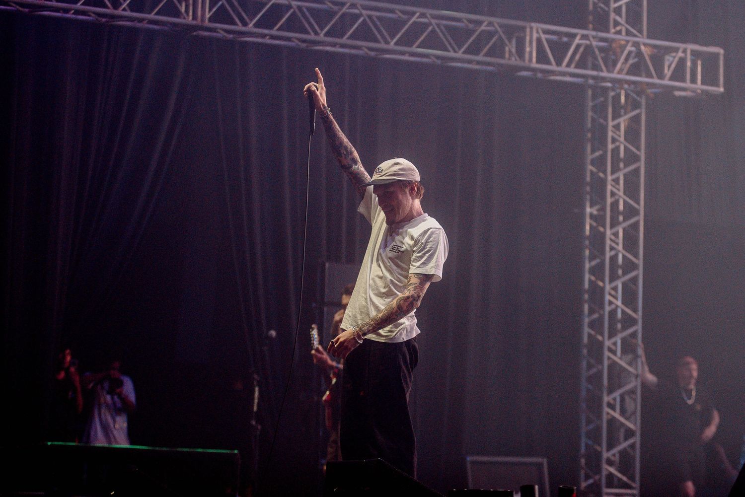 Concert performer raises arm during dramatic stage performance with spotlight.