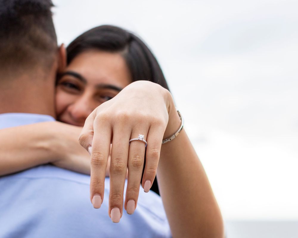 Orange County photographer captures Newly engaged woman showing diamond ring while embracing her partner outdoors.