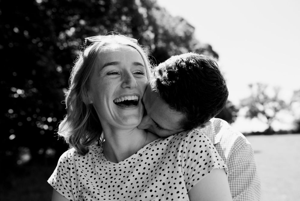 Candid black and white photograph showing joyful laughter and affection outdoors.