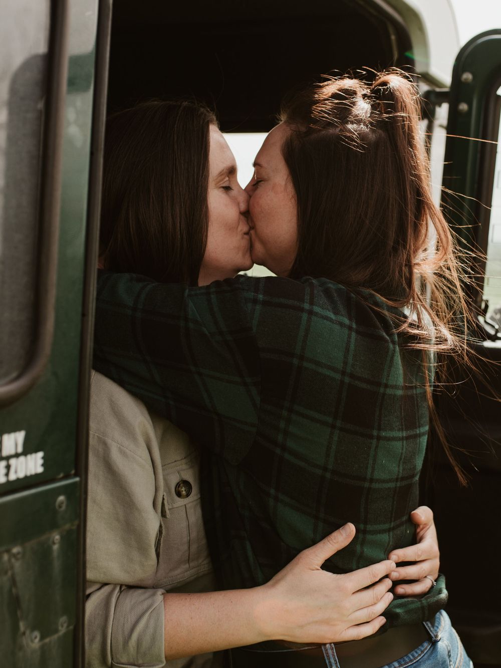 A moody black and white portrait of two people sharing an intimate moment in a car.