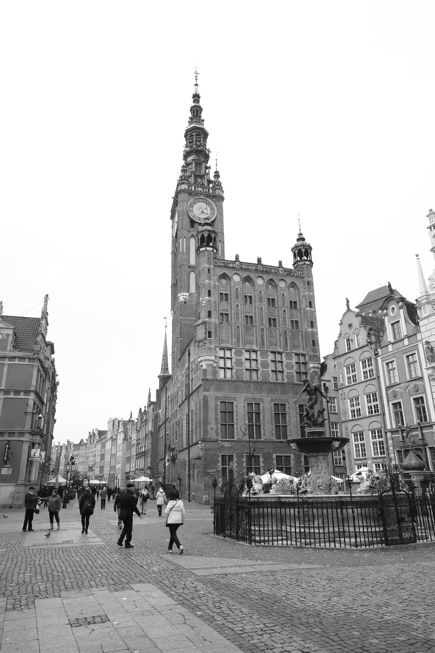 Historic Gothic town hall with ornate clock tower and cobblestone streets in the old town square of Gdansk, Poland.