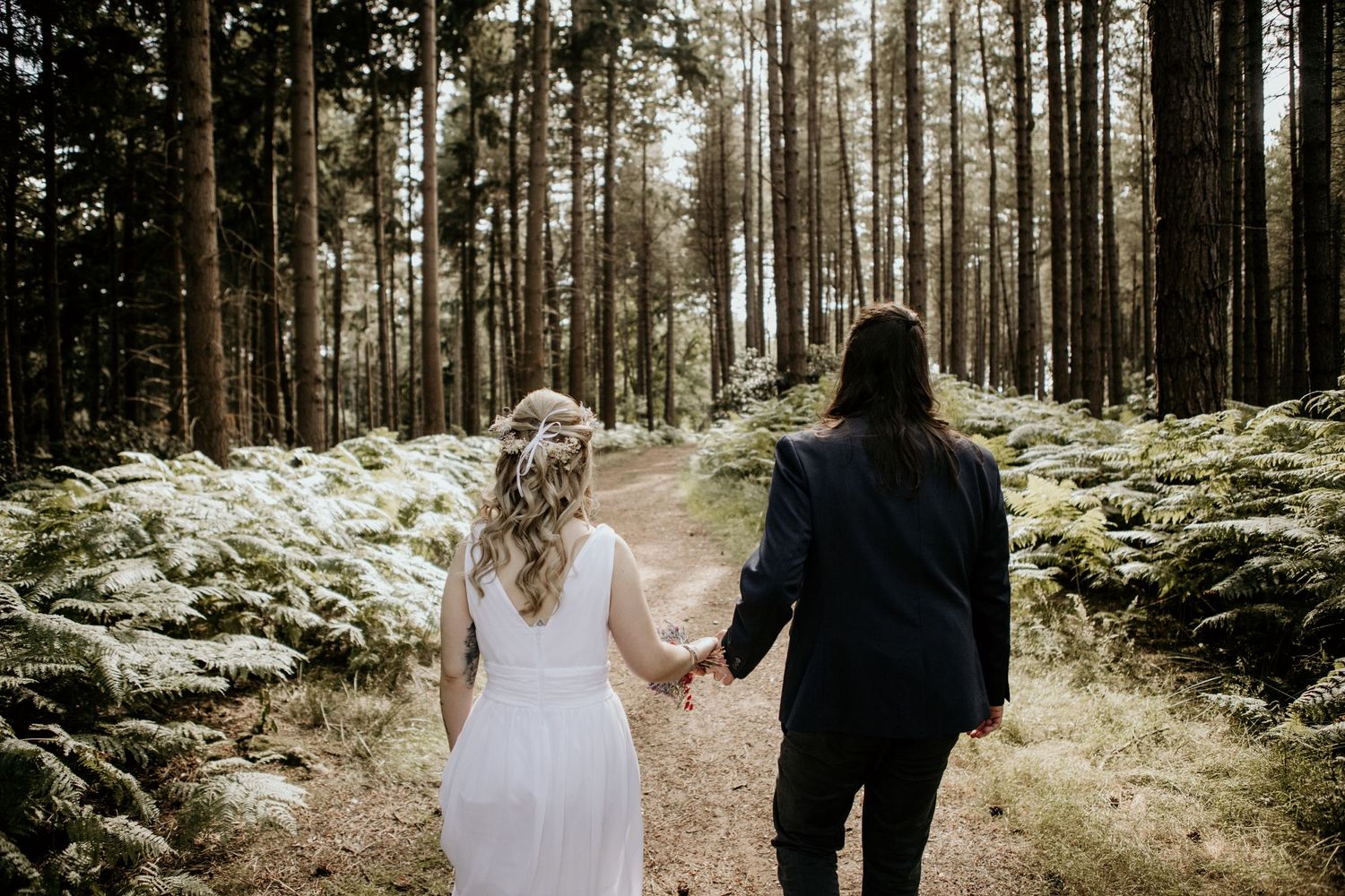 bride and groom walking through woods