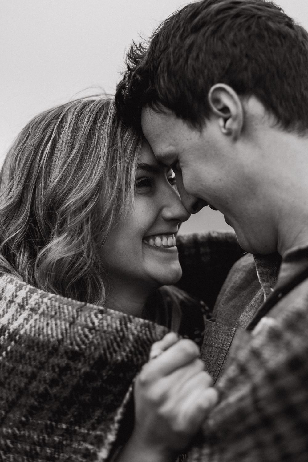 Engaged couple wrapped up in a blanket