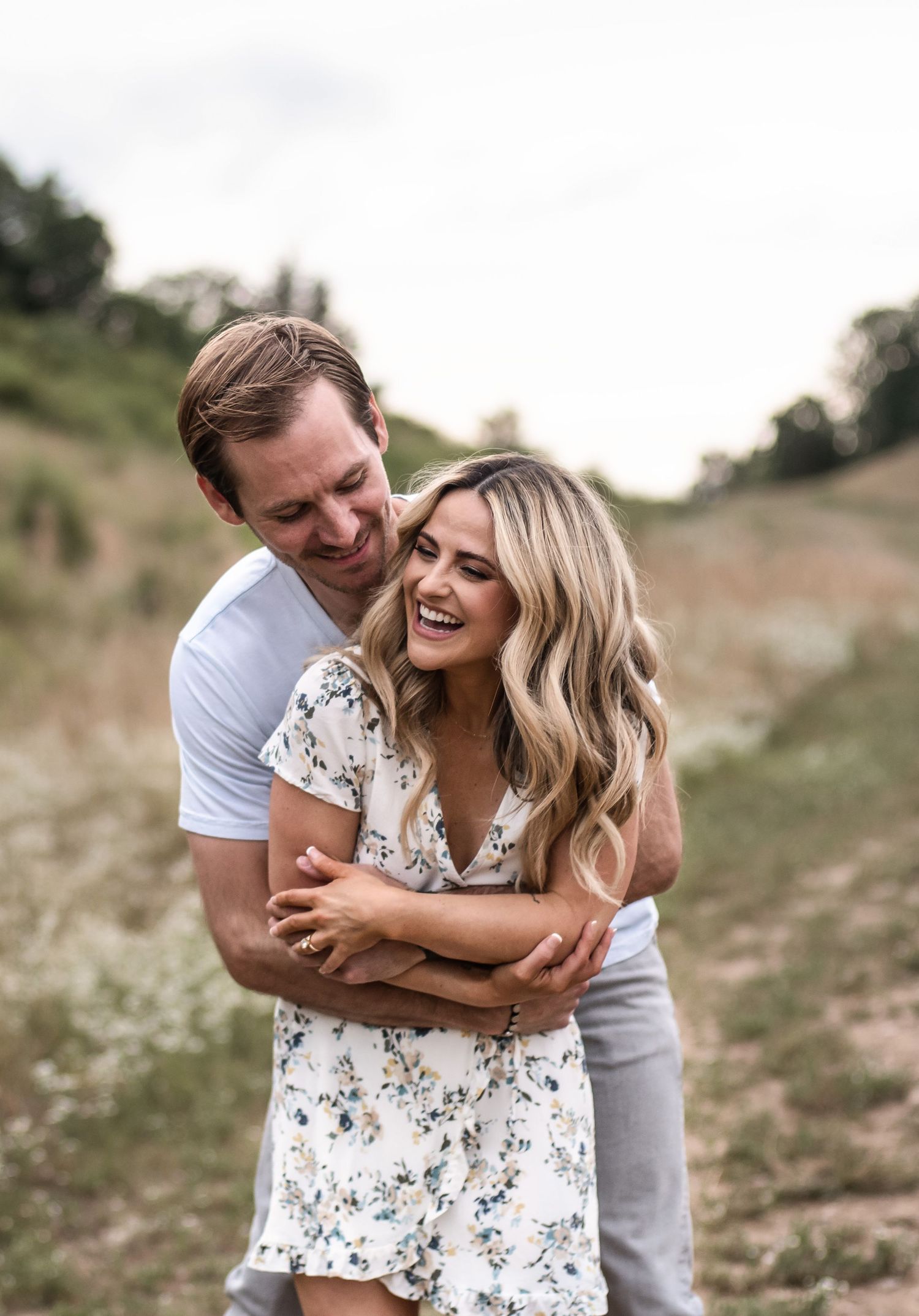 Candid engagement photos of couple laughing and embracing in natural outdoor setting.