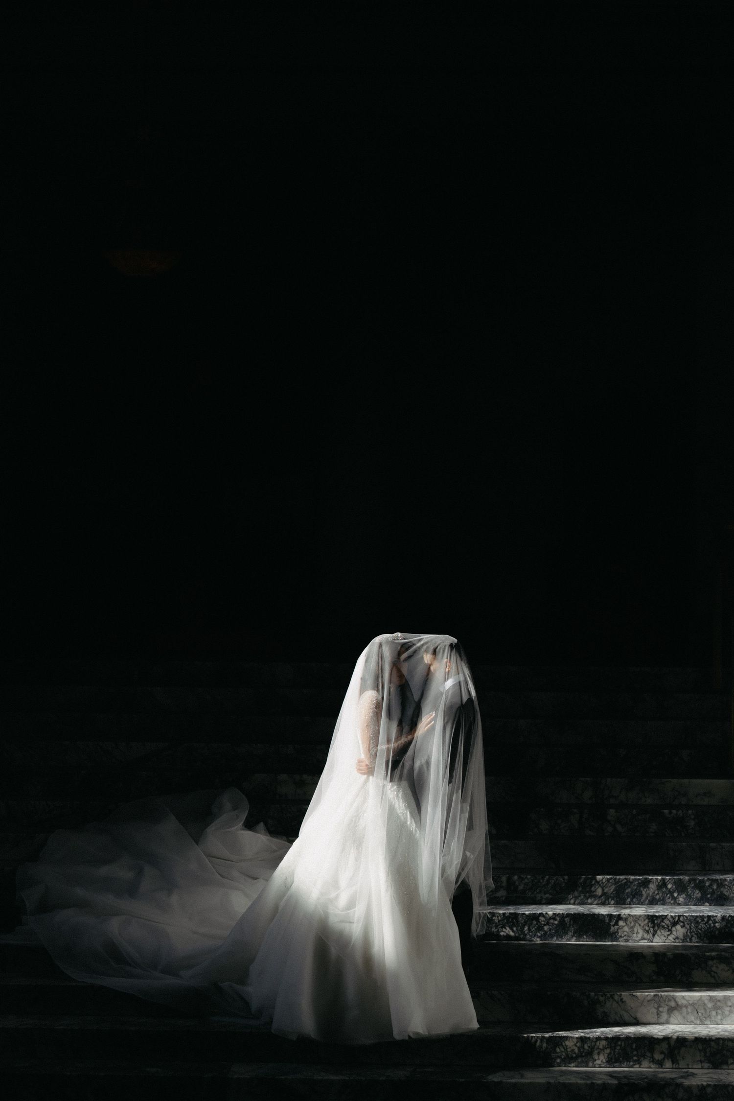 Bride and groom under the veil on a marble staircase inside of the capitol building in Olympia