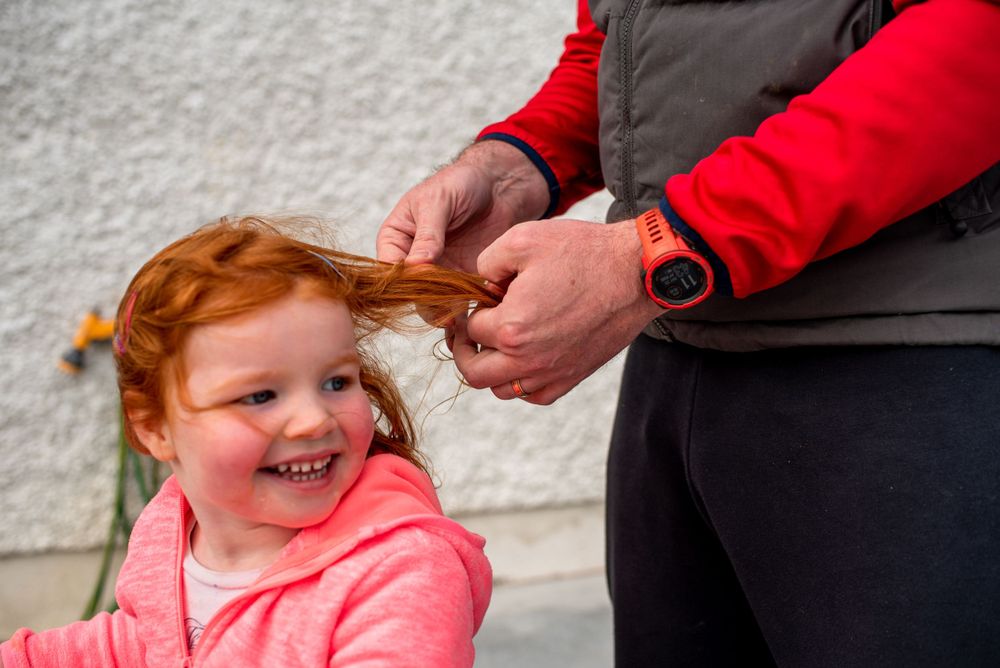 Tender moment shared outdoors against white wall.