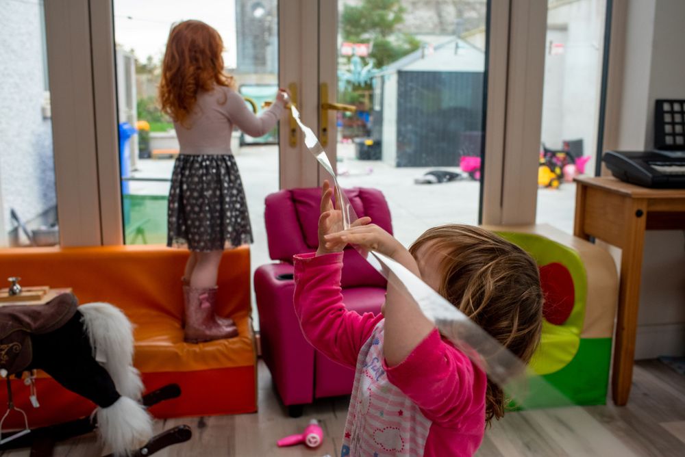 Two people playing and dancing in a bright living room with colorful furniture.