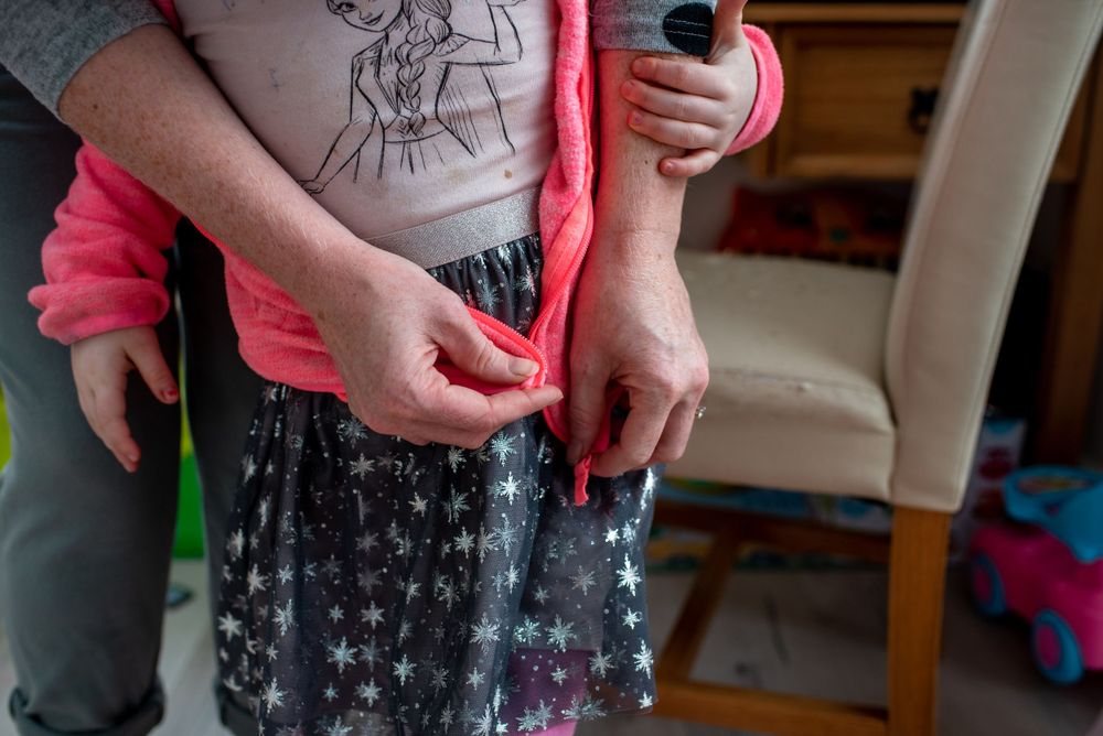 Hands adjusting star-patterned skirt with pink sweater.