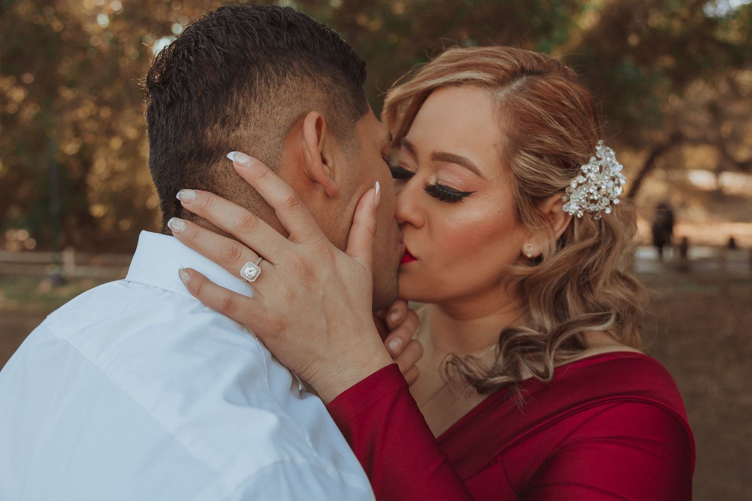 Intimate embrace shared between couple with autumn scenery in background.