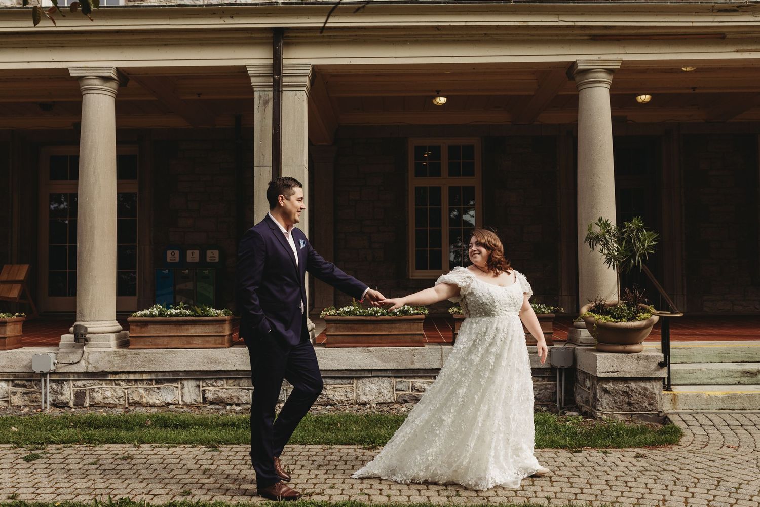 Couple dancing together on the patio of an elegant stone mansion with classical columns.