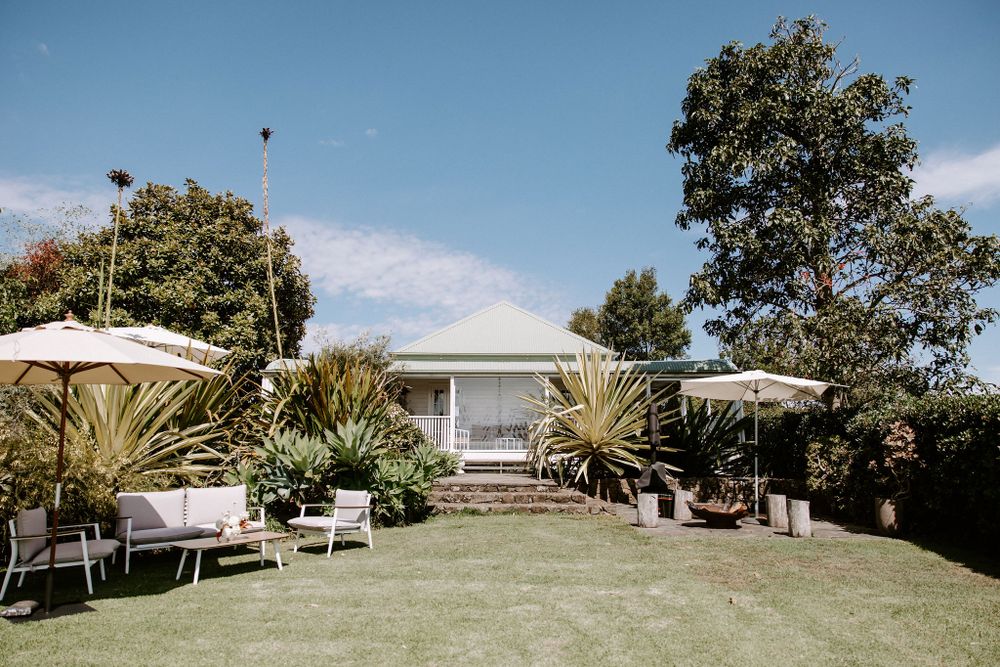 Outdoor wedding venue with white house, manicured lawn and contemporary garden furniture.