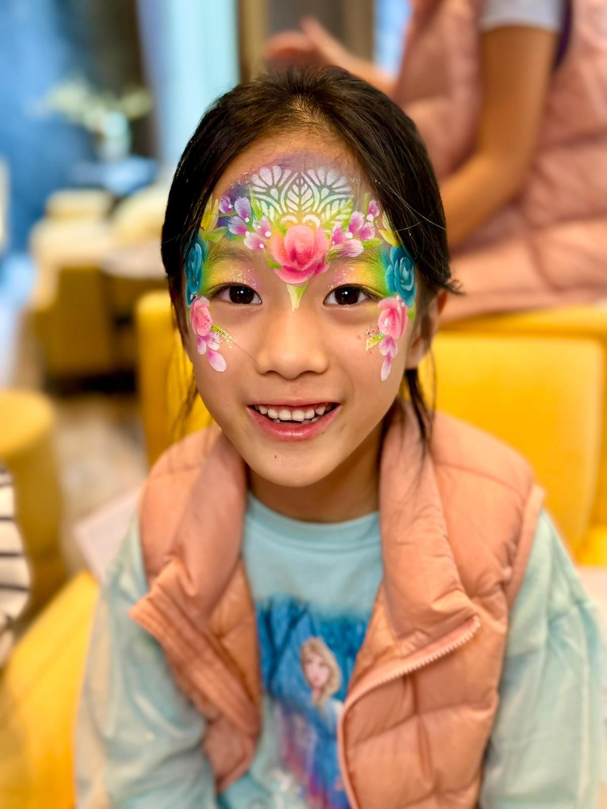 Delicate floral face paint design with pink roses and turquoise accents.