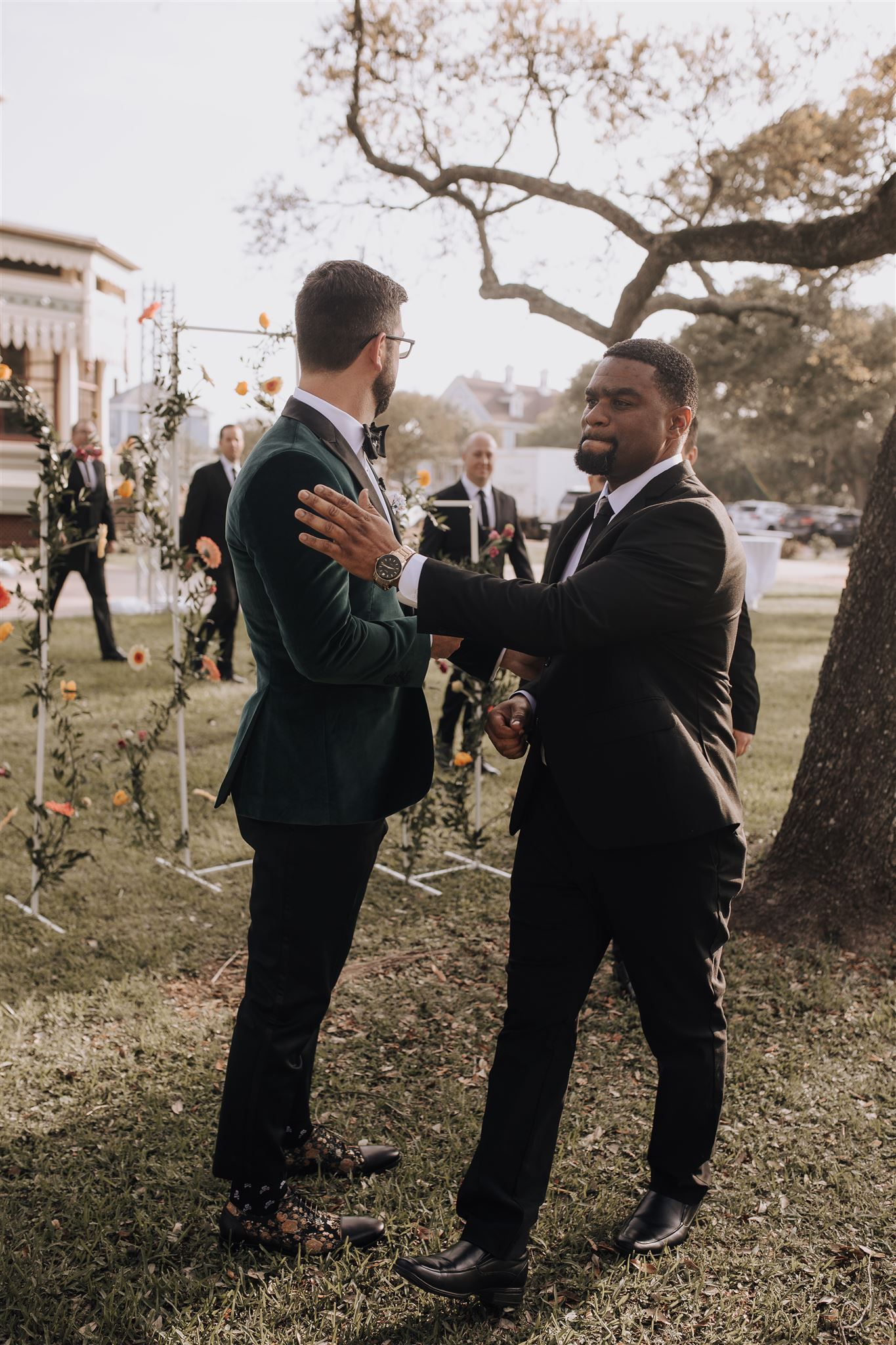 Two people in formal attire sharing an emotional moment outdoors during a wedding ceremony.