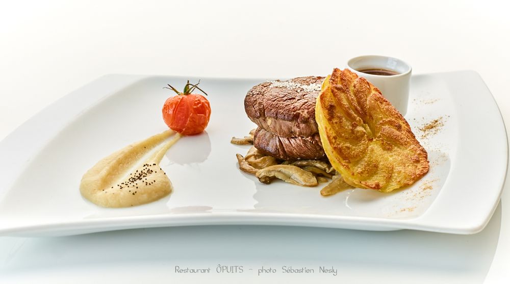 Fine dining meat course with sauce and garnish elegantly plated on white dish.