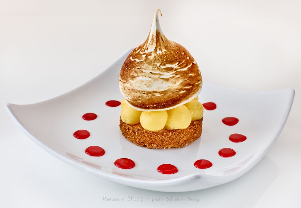 Elegant dessert with raspberry coulis dots arranged on white plate.