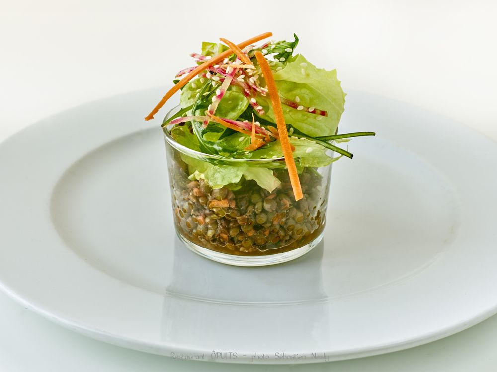 Fresh green salad with carrot strips and herbs served in modern presentation.