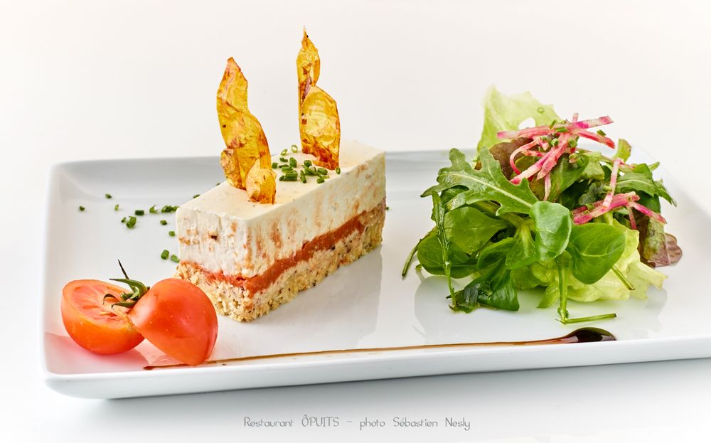 Fresh tomato and greens appetizer artfully presented on long white plate.