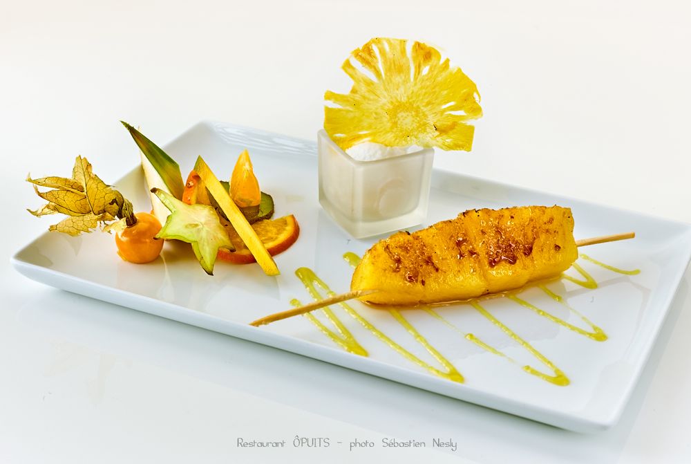 Golden-fried seafood dish with yellow sauce and fresh herbs on modern white plating.