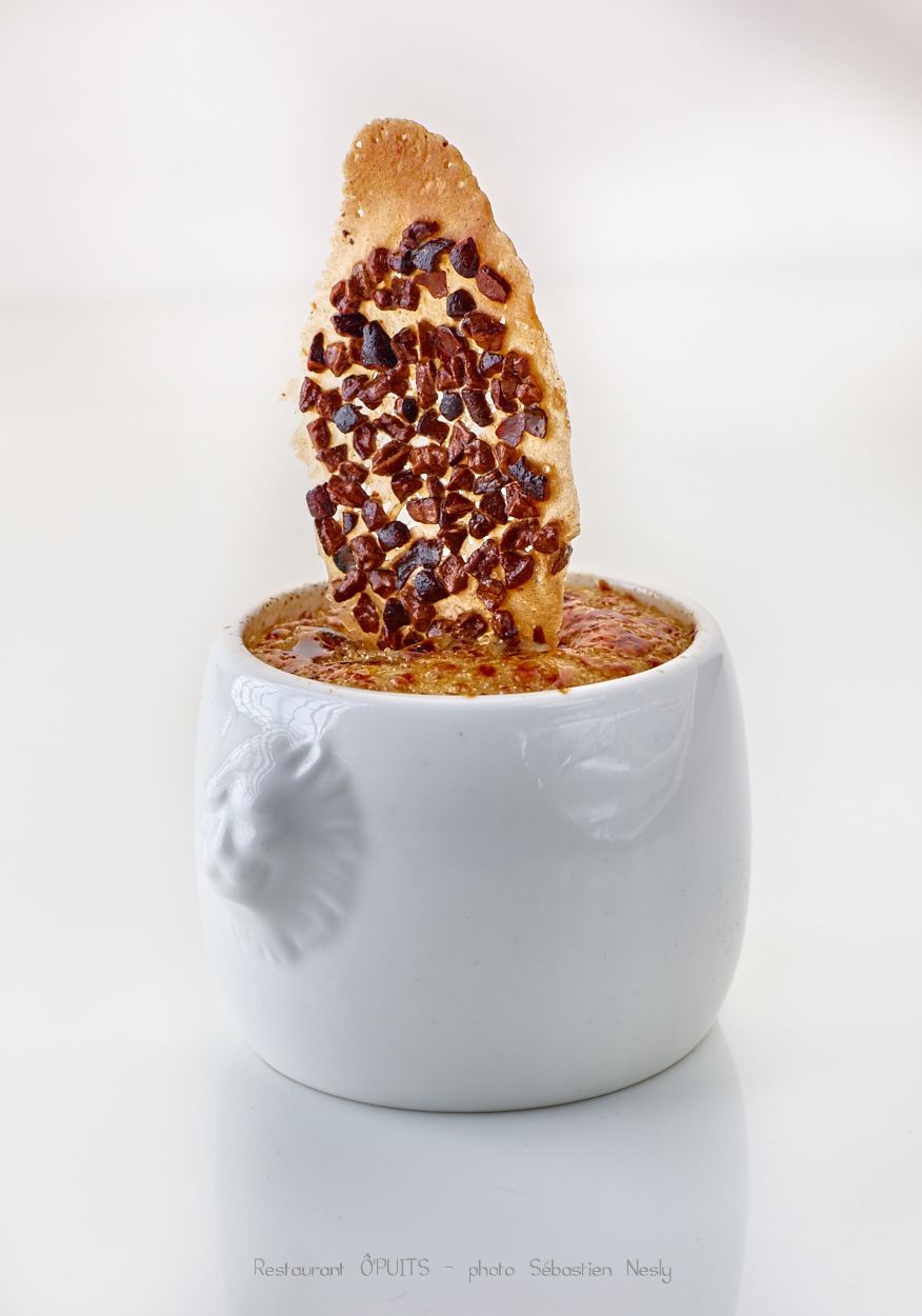 A chocolate-covered biscotti stands in a white ceramic cup filled with coffee.