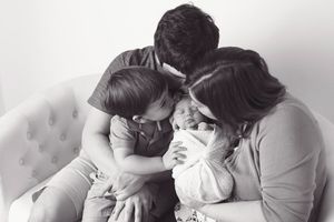 Black and white intimate family moment on light colored sofa.