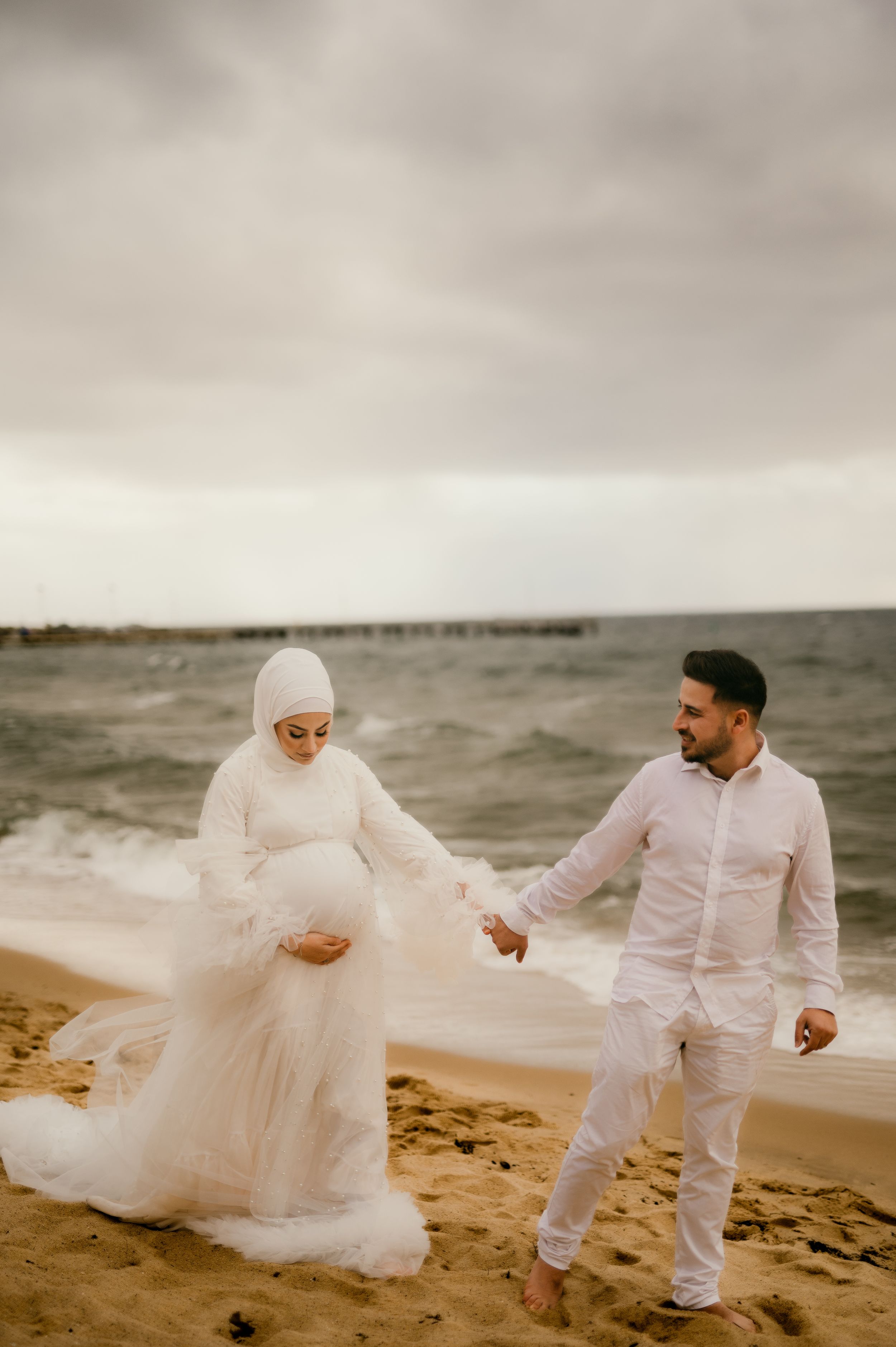 A romantic beach scene shows two figures in white attire walking together by the ocean.