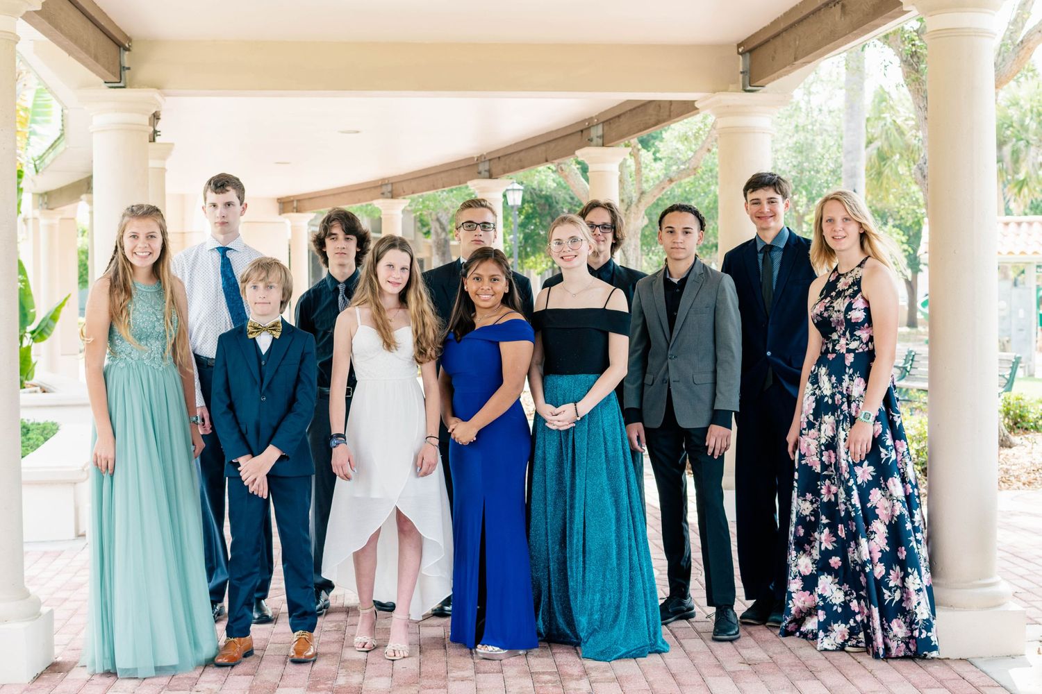 Group photo of people in formal wear standing under covered porch.