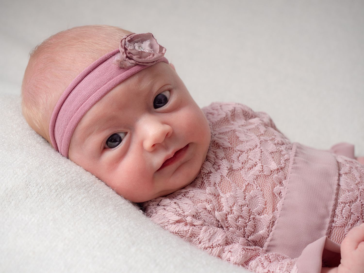 baby in pink headband looking at camera
