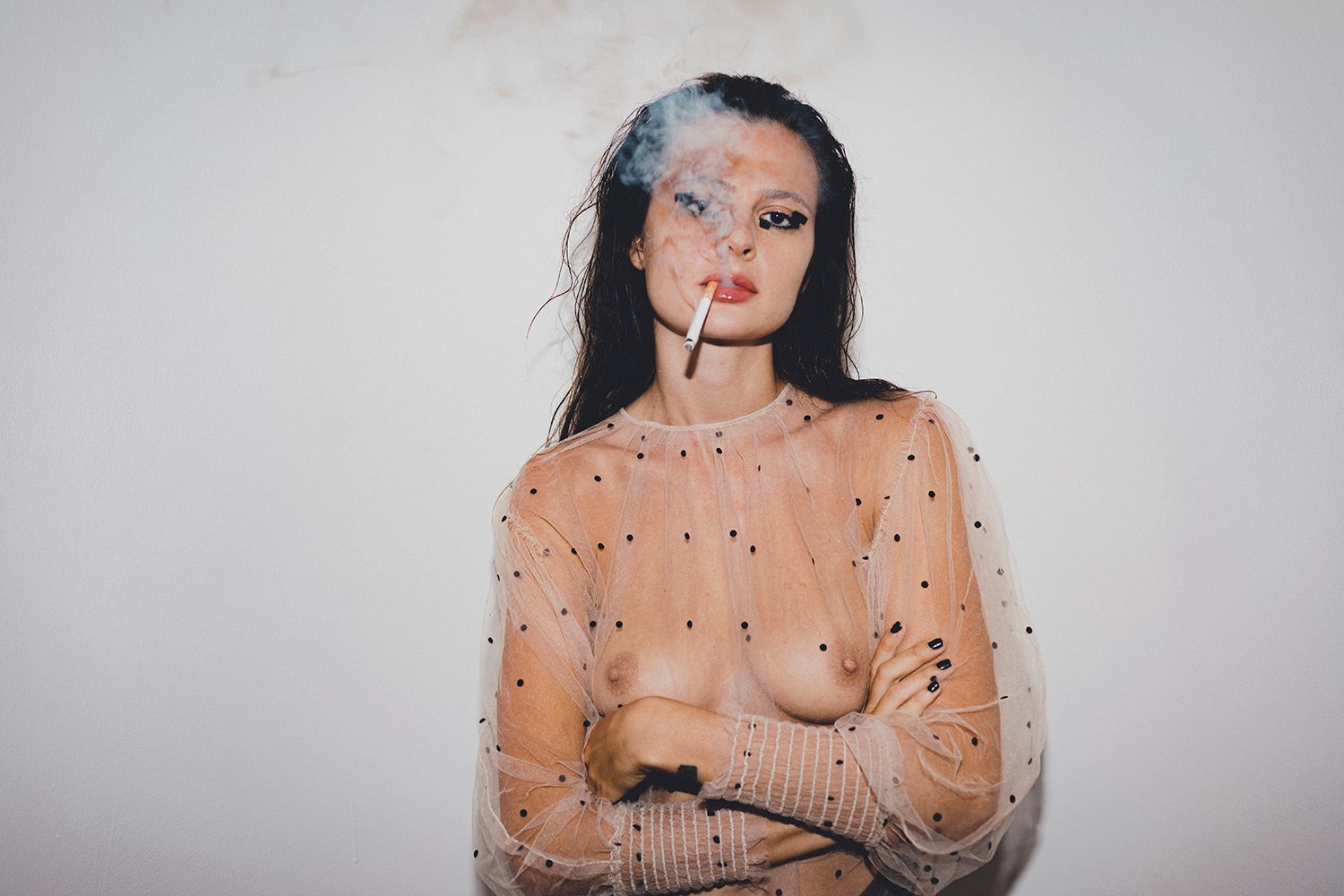 Person wearing sheer sparkly top against white background in artistic portrait.