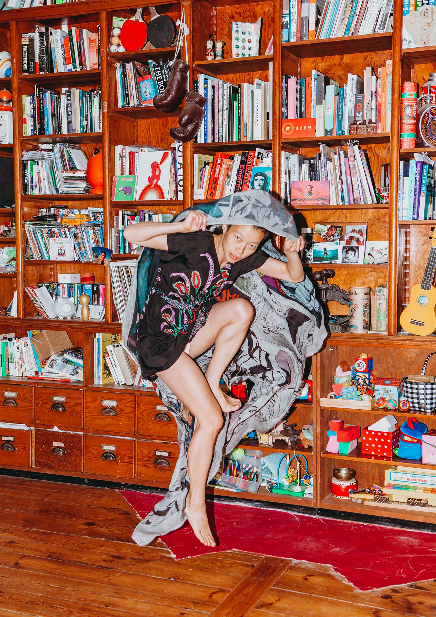 Sequence of someone jumping and flipping on a red carpet in front of wooden bookshelves in a library setting.
